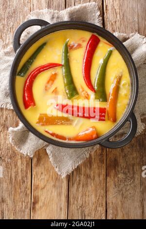 EMA datshi è uno dei piatti più famosi della cucina bhutanese, è fatto di peperoncini piccanti e di formaggio in primo piano nella padella sul tavolo. Verticale Foto Stock