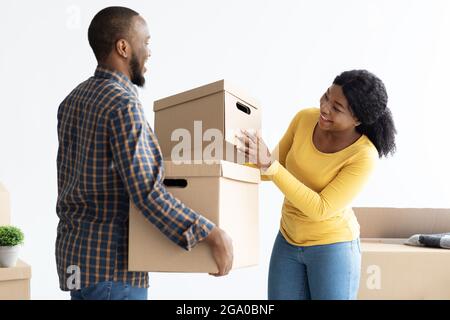 Giorno in movimento. Ritratto di gioiosi sposi giovani neri con scatole di cartone Foto Stock