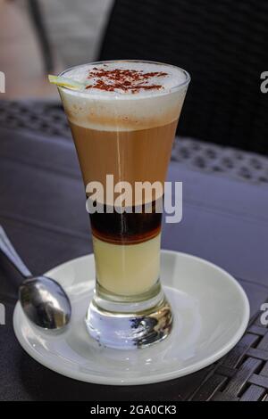 Caffè con latte, il Liquore di cannella e limone in un vetro su una tavola nera Foto Stock