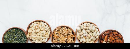 Diversi tipi di frutta a guscio in ciotole di legno, come le noci di anacardi, le nocciole, le noci, le mandorle tranciate, il brasile, pistacchi arrostiti, semi di zucca. Sano s Foto Stock