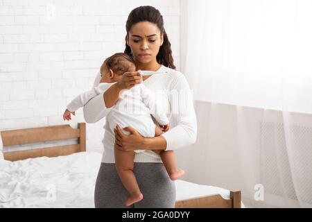 Afroamericano Mon con figlio infante malato che ha febbre Indoor Foto Stock