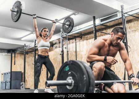 coppia di uomo e donna che fanno pesi in palestra, crossfit Foto Stock