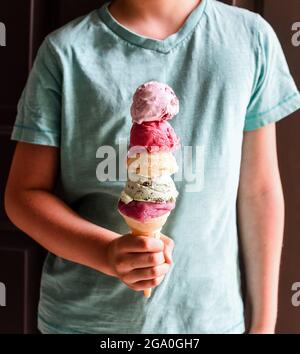 Primo piano del cono per gelato multi-cucchiaio per la mano del bambino. Foto Stock