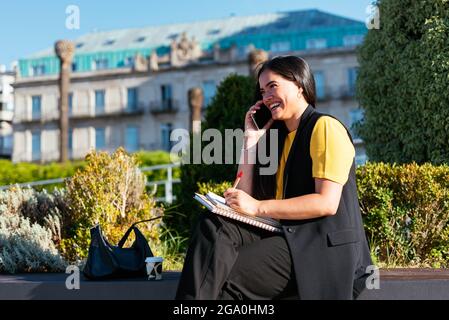 Giovane donna di affari che scrive e parla al telefono sulla strada Foto Stock