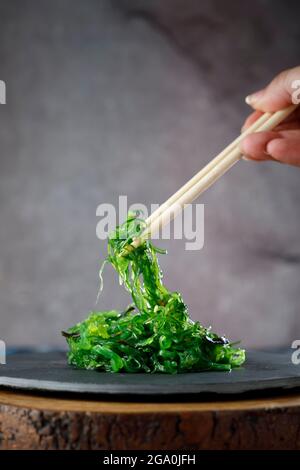 Insalata di wakame tenuta con bastoncini di legno Foto Stock