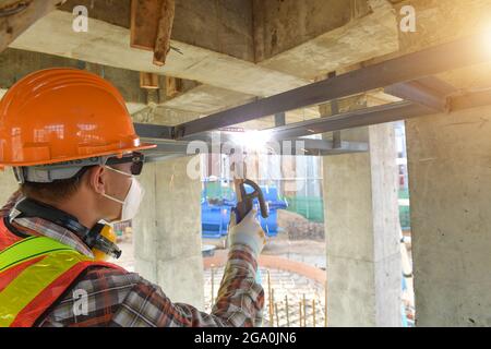 Tubi di saldatura per lavoratore con scintilla antincendio nel sito di costruzione, acciaio per saldatura industriale Foto Stock