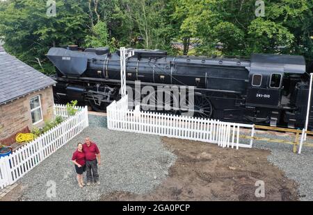 Simon e Diana Parums con il loro treno a vapore di dimensioni complete con carrozze, piste e piattaforma, mentre convertirono e restaurarono la stazione del lago Bassenthwaite a Keswick, offrendo un'esperienza culinaria su una carrozza ristorante di Hollywood come il suo pezzo forte, quando la aprono al pubblico come attrazione. Data immagine: Mercoledì 28 luglio 2021. Foto Stock