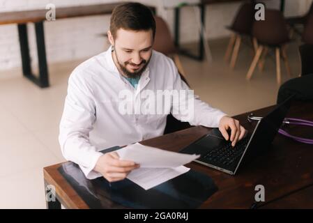 Ritratto di giovane medico concentrato che indossa cappotto bianco leggendo la documentazione medica Foto Stock