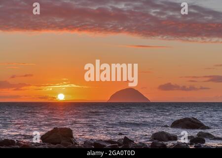 Tramonto sul Mare d'Irlanda e Ailsa Craig preso da Lendalfoot, Sud Ayrshire, Scozia con rocce in primo piano Foto Stock