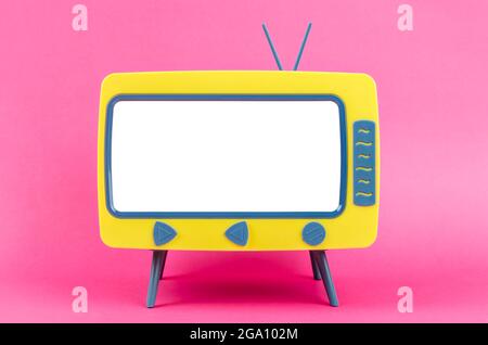 Televisione giocattolo in miniatura vintage su sfondo rosa. Foto Stock