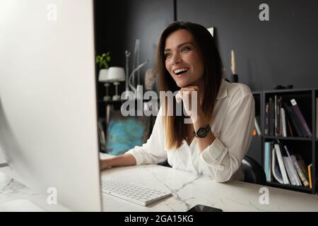 Giovane donna attraente che lavora in ufficio, utilizzando un computer desktop moderno. Foto Stock