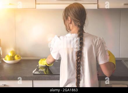 Giovane caucasica ragazza pulizia e lucidare cucina elettrica, piano tavolo nella cucina moderna Foto Stock