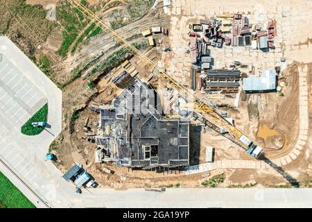 costruzione di un alto edificio di appartamenti. piano in costruzione. gru gialla funzionante. vista aerea dall'alto. Foto Stock