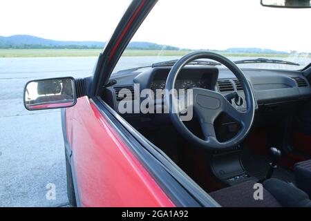 L'interno della classica giovane macchina timer degli anni '80. Il volante e il cruscotto sono visibili attraverso il finestrino laterale Foto Stock