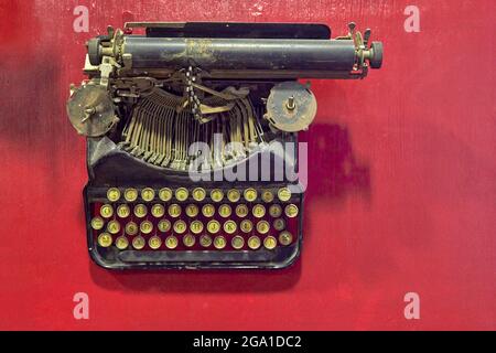 vecchia macchina da scrivere nera invecchiata, vista dall'alto e sfondo rosso. orizzontale e spazio di copia Foto Stock