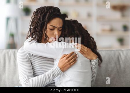 Bambina nera che piange sulla spalla delle madri Foto Stock