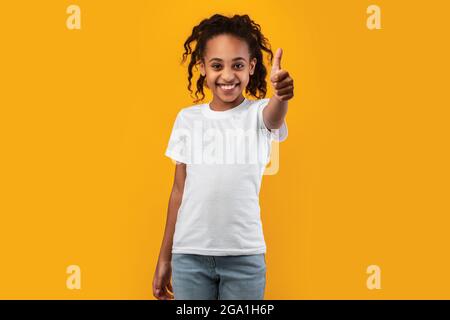 Felice ragazza nera gesturing pollice su e sorridente Foto Stock