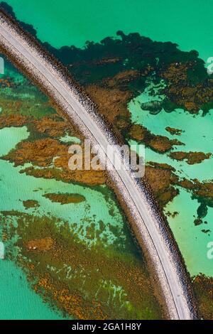 Vista aerea dal drone della strada rialzata di Eriskay che collega le isole del Sud Uist (in alto) a Eriskay nelle Ebridi esterne, Scozia, Regno Unito Foto Stock