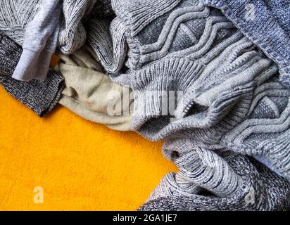 Caldi jumper e pullover in maglia su sfondo giallo brillante. Foto Stock