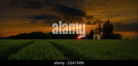 Incredibile tramonto e alba sul mulino a vento e sul campo di grano. La foto migliore Foto Stock