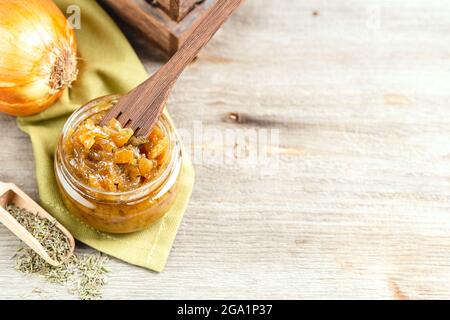 Marmellata di cipolle in un vaso di vetro su un tavolo di legno. Cipolla confiture conservazione fatta in casa Foto Stock
