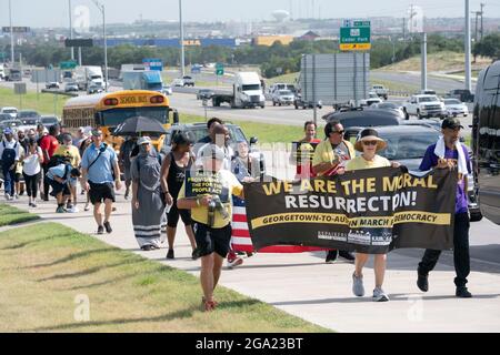 Georgetown, Stati Uniti. 28 luglio 2021. Gli attivisti per i diritti di voto nazionali e del Texas che detengono il banner "We are the Moral Resurrection" iniziano una marcia di 30 miglia, quattro giorni, da Georgetown, Texas, al Campidoglio di Stato di Austin. A causa del caldo estivo del Texas, diversi turni da 100 persone si scambieranno di marcia per circa 4 miglia ciascuno. La marcia per la democrazia sollecita l'approvazione della legge sui diritti di voto di John Lewis e l'eliminazione delle barriere statali al voto. Credit: Bob Daemmrich/Alamy Live News Foto Stock