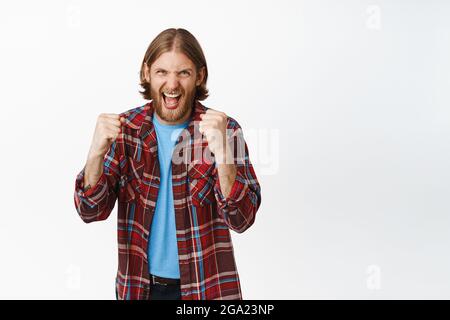 Sì, portalo su. L'uomo biondo entusiasta, canta e canta il pugno eccitato speranzoso, guardando una partita emozionante, radicando per la squadra preferita, s tanding Foto Stock