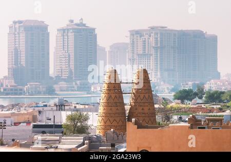 Skyline urbano con le torri degli uccelli e i moderni grattacieli di Doha, Qatar Foto Stock
