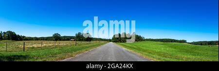 Banner web panoramico di una strada di campagna vuota con terreno agricolo su entrambi i lati e spazio negativo sopra. Foto Stock