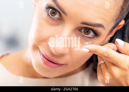 Una giovane donna mette lenti a contatto negli occhi. Foto Stock