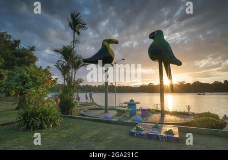 Una famiglia si affaccia sul corso d'acqua mentre il sole tramonta sul villaggio di Tortuguero, Costa Rica; Tortuguero, provincia di Limon, Costa Rica Foto Stock