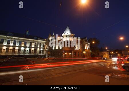 L'edificio illuminato con tracce di luci rosse per auto. Boulevard Ring. Binari del tram su strada asfaltata. Foto serale del centro storico di Mosca. Foto Stock