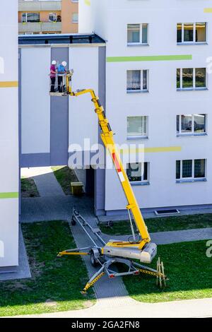 lo specialista ispeziona la facciata della casa con l'aiuto di una moderna piattaforma di sollevamento idraulico semovente mobile Foto Stock