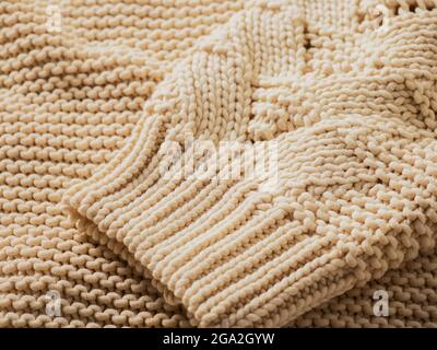 Estremo primo piano del bracciale di un pullover in maglia color crema; studio Foto Stock