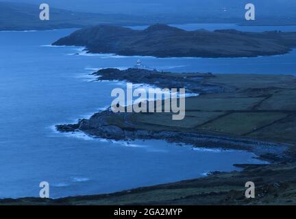 Vista aerea delle onde che si infrangono nelle ore precedenti l'alba a Valentia Island Lighthouse a Cromwell Point, costruito sul sito del 17th secolo Cromwell ... Foto Stock