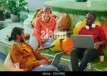 Felici i giovani dirigenti interculturali di un grande ufficio open space contemporaneo brainstorming e discutere di nuove idee alla riunione iniziale Foto Stock