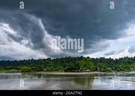 Nuvole di tempesta che si formano sul villaggio lungo il fiume lungo la giungla coperto rive del fiume Ayeyarwady (Irrawaddy) Foto Stock