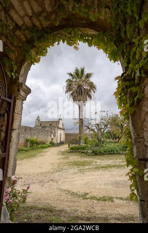 Vista attraverso un arco verso un giardino appartato con nuvole grigie su una villa italiana nelle colline sopra Ostuni; Ostuni, Puglia, Italia Foto Stock