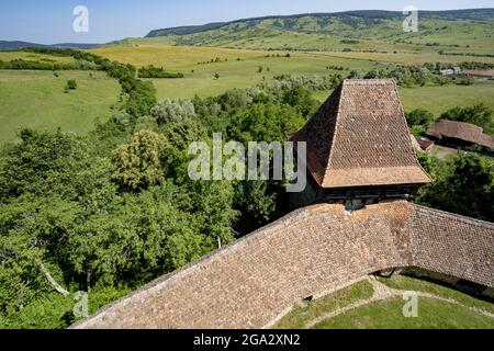 Tetto della Chiesa sassone fortificata di Viscri con le sue mura di pietra e panoramica del villaggio; Viscri, Contea di Brasov, Transilvania, Romania Foto Stock
