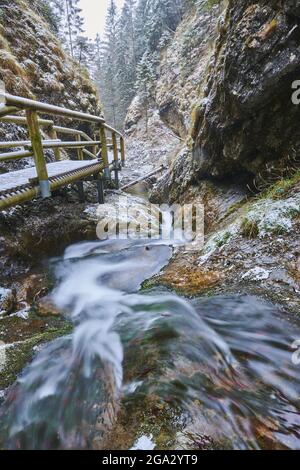 Primo piano del fiume innevato con un ponte pedonale che si snodano intorno al canyon roccioso a Janosikove DIERY in inverno Foto Stock