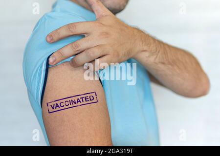 Uomo caucasico, paziente con bollo blu vaccinato a portata di mano. Concetto di vaccinazione delle persone per il coronavirus covid-19, influenza, malattie infettive. Iniezione Foto Stock