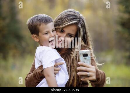 Una madre che passa a fotoritratti mentre si gode di un tempo di qualità insieme all'aria aperta in un parco cittadino; Edmonton, Alberta, Canada Foto Stock