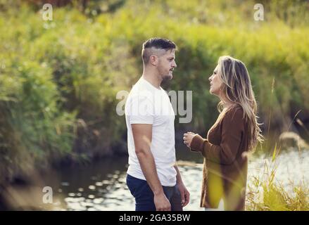 Marito e moglie trascorrono del tempo di qualità all'aperto vicino a un ruscello in un parco cittadino e hanno una discussione seria; Edmonton, Alberta, Canada Foto Stock