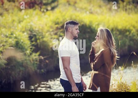 Marito e moglie trascorrono del tempo di qualità all'aperto vicino a un ruscello in un parco cittadino e hanno una discussione seria; Edmonton, Alberta, Canada Foto Stock