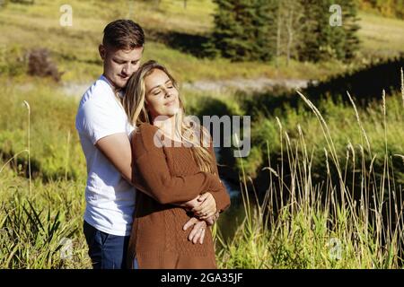 Marito e moglie trascorrono del tempo di qualità all'aperto vicino a un ruscello in un parco cittadino; Edmonton, Alberta, Canada Foto Stock