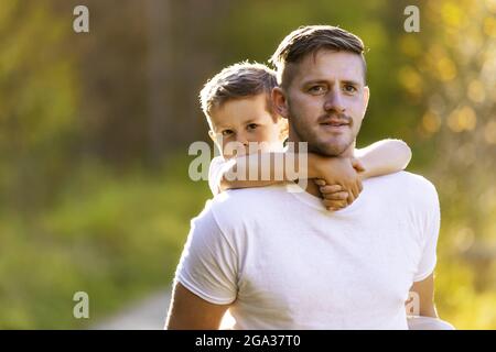 Un padre che riporta il figlio Piggy durante una gita in famiglia in un parco cittadino durante la stagione autunnale; Edmonton, Alberta, Canada Foto Stock