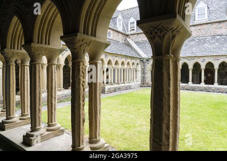 Colonne scolpite costeggiano il cortile interno dei chiostri dell'Abbazia benedettina sull'isola di Iona, Scozia; isola di Iona, Scozia Foto Stock