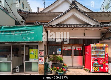 tokyo, giappone - luglio 15 2021: Il tradizionale bagno giapponese Atamiyu a Kagurazaka con un distributore automatico di bevande e fiori di fronte e una moneta lau Foto Stock