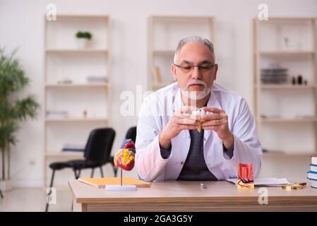 Vecchio insegnante di dentista seduto in classe Foto Stock