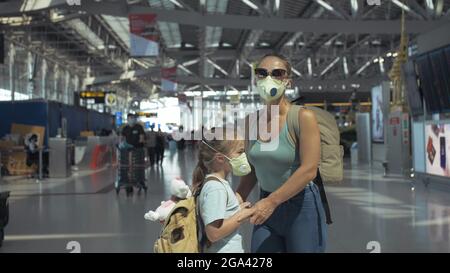 Donna e bambino turista caucasico in aeroporto con indossare maschera medica protettiva. Famiglia in isolamento quarantena. Coronavirus covid-19. Foto Stock